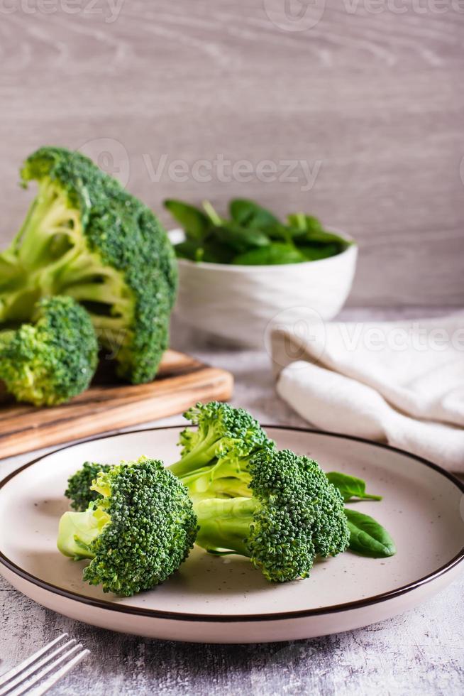 Fresh broccoli divided into inflorescences on a plate on the table. Vegetable diet. Vertical view photo