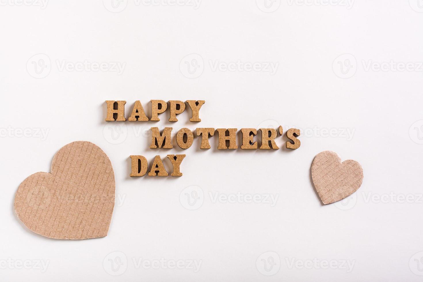 Happy mother's day. Wooden letters and cardboard hearts on a light background. photo