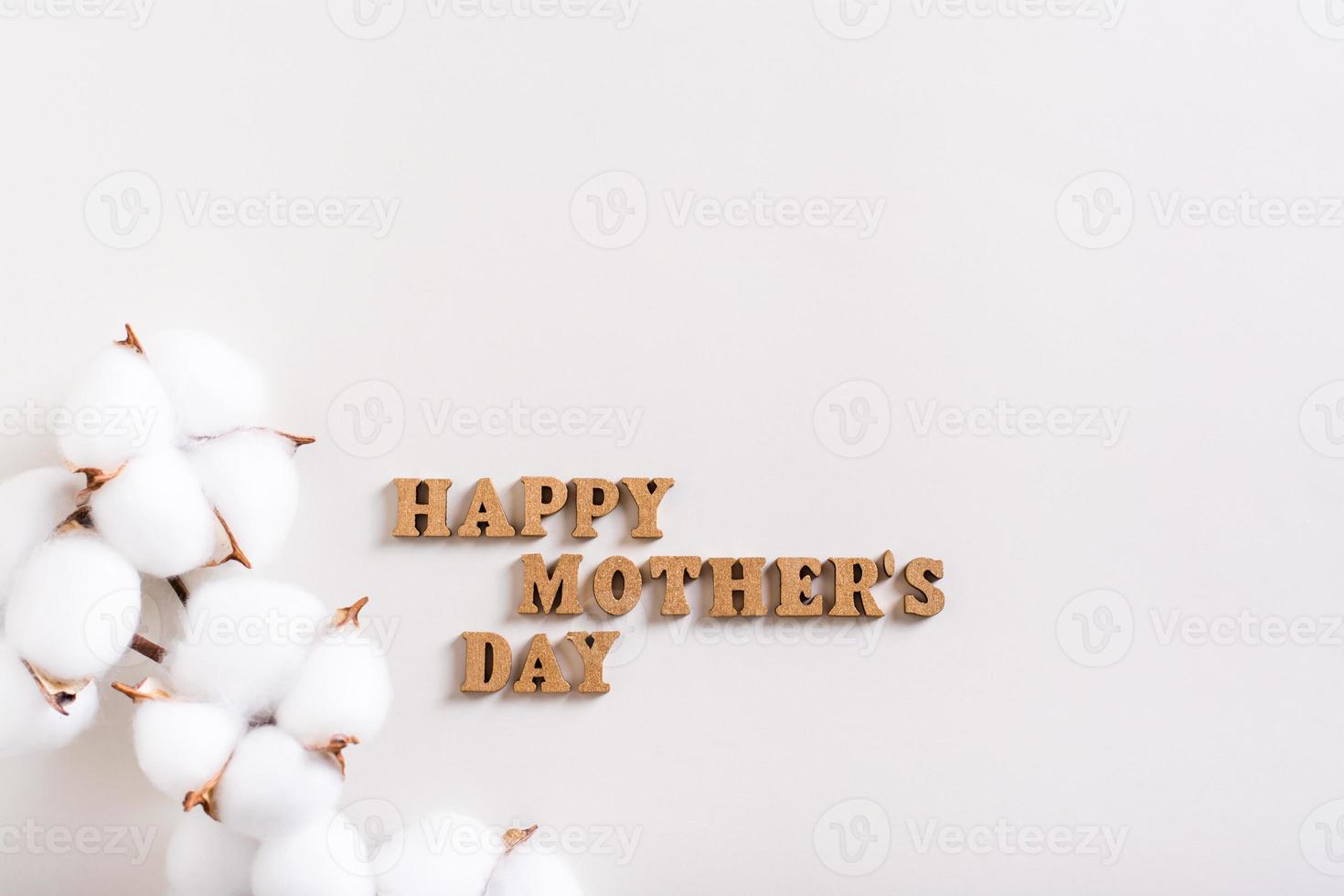 Happy mother's day. Wooden letters and a branch of cotton on a light background. photo