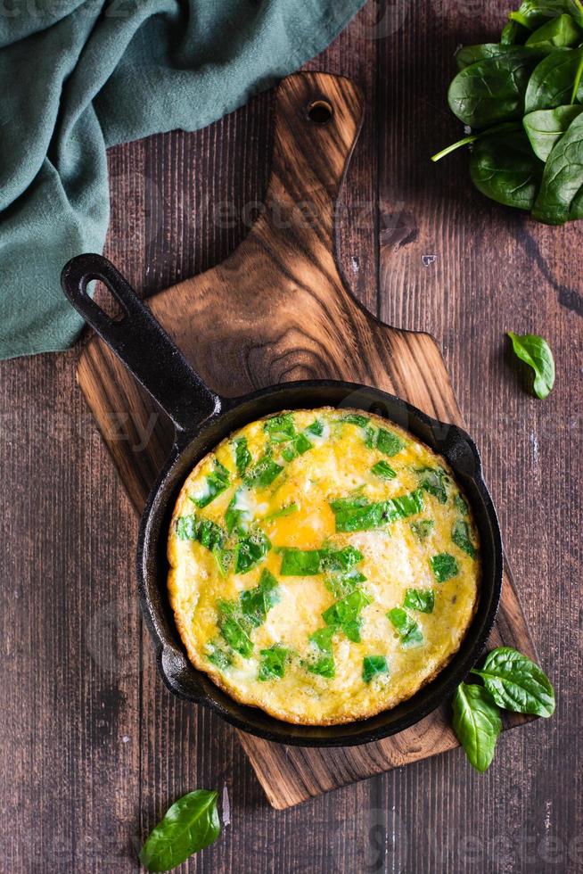 Omelet stuffed with spinach in a pan for breakfast. Homemade food. Top and vertical view photo