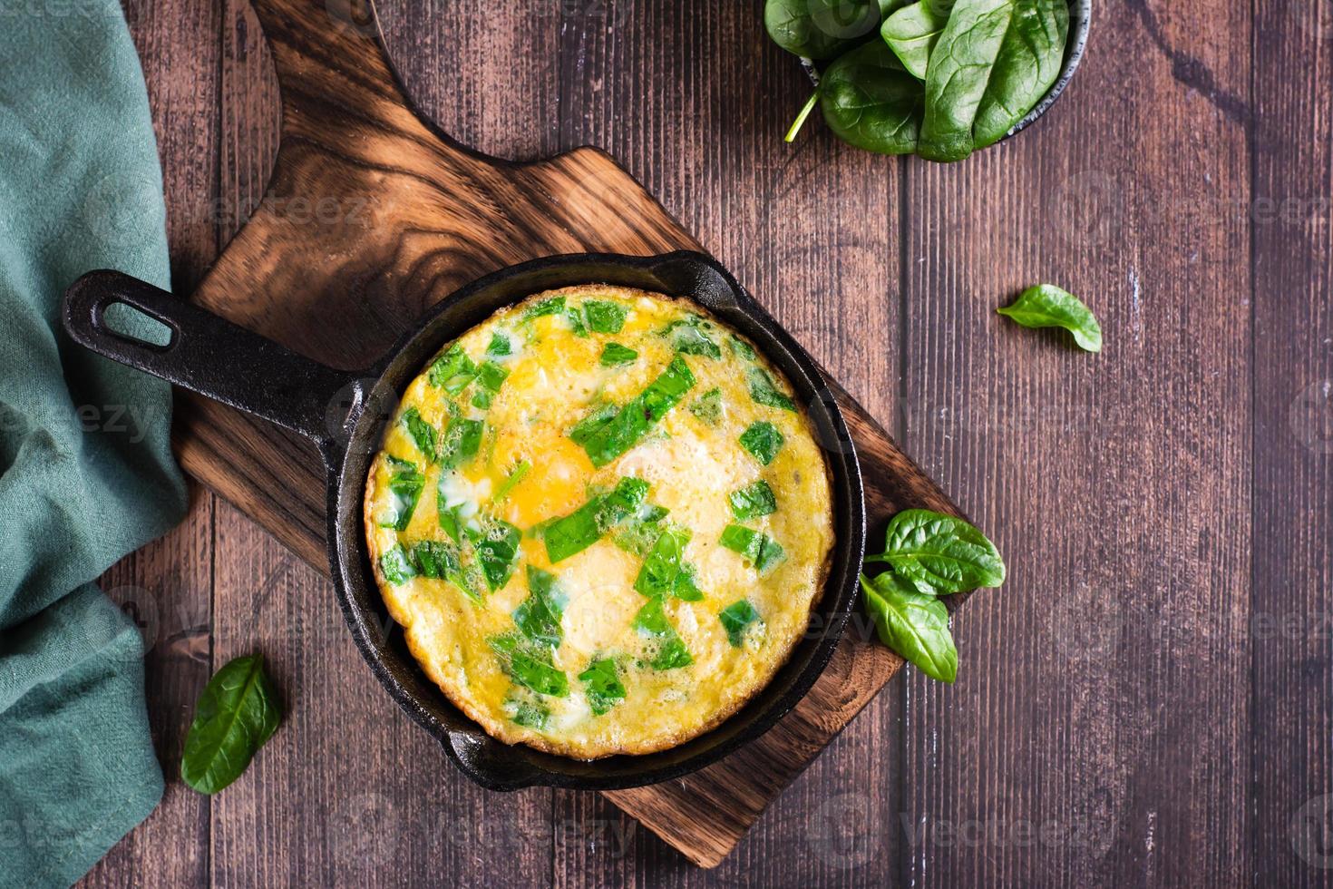 tortilla con espinacas y queso en una sartén sobre la mesa. dieta cetogénica. vista superior foto