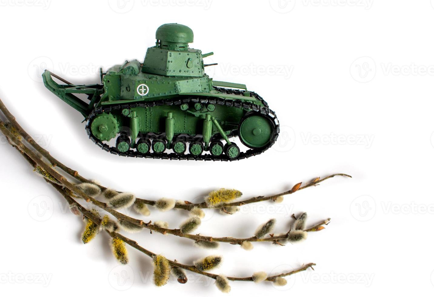 modelo de un viejo tanque soviético hecho de papel sobre un fondo blanco. rama de sauce en primer plano. vista lateral. foto
