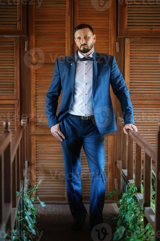 portrait of a groom with a beard in a blue suit photo