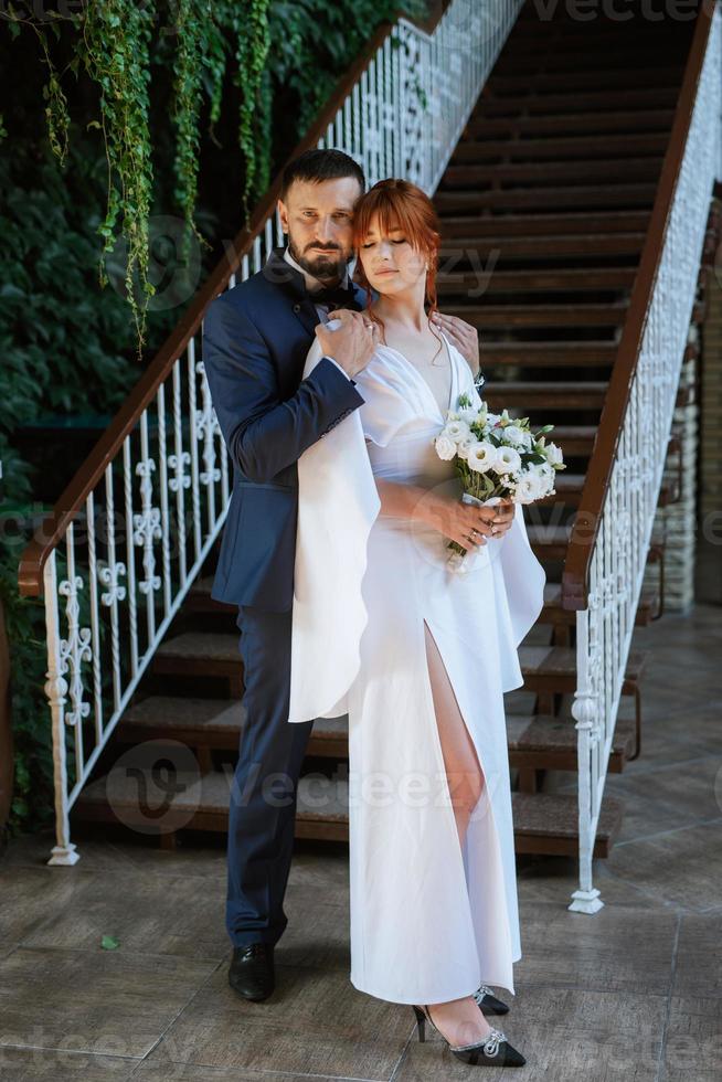 bride in a white dress with a bouquet and the groom in a blue suit photo