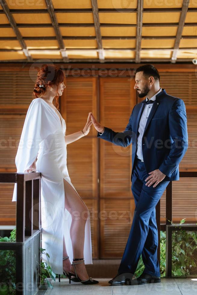 bride in a white dress with a bouquet and the groom in a blue suit photo