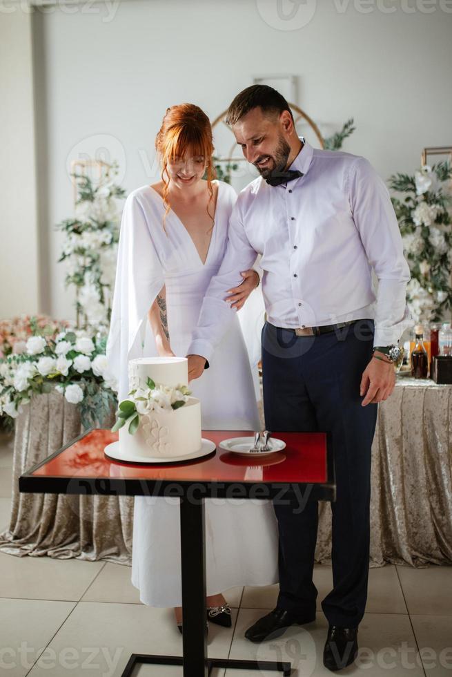 los recién casados felizmente cortan y prueban el pastel de bodas foto