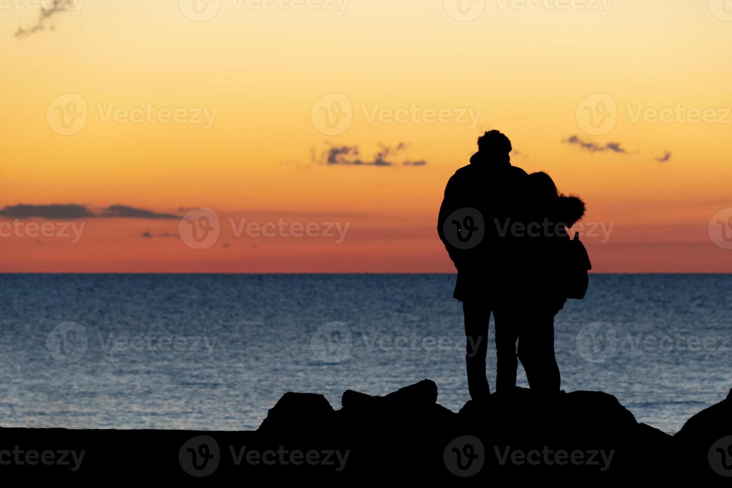 lovers hugging in front of the sea at sunset photo