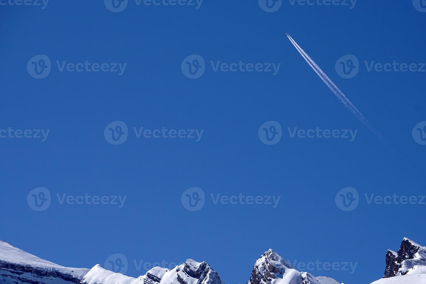 Airplane trails tracks chemtrails in the deep blue sky photo