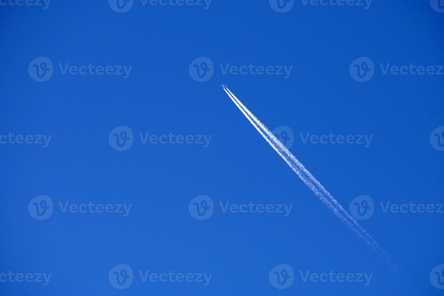 Airplane trails tracks chemtrails in the deep blue sky photo