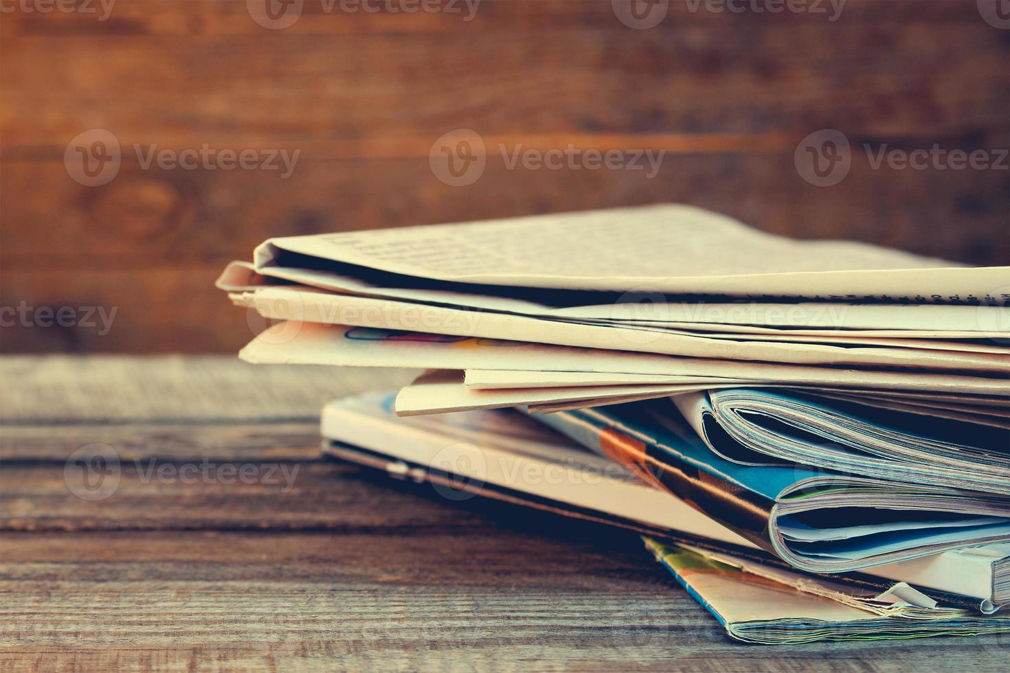 Newspapers and magazines on old wood background. Toned image. photo