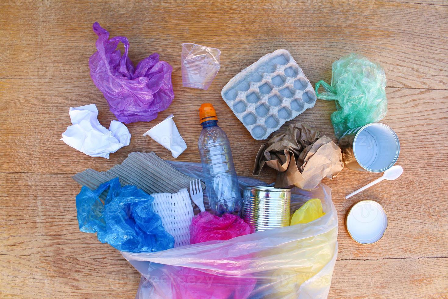 Garbage bag with different trash on wooden background. Top view. Flat lay. photo