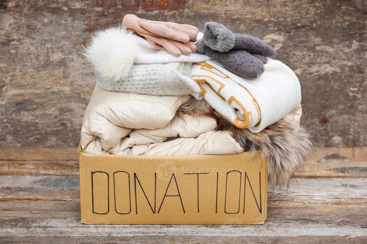 Donation box with winter clothes on an old wooden background. photo