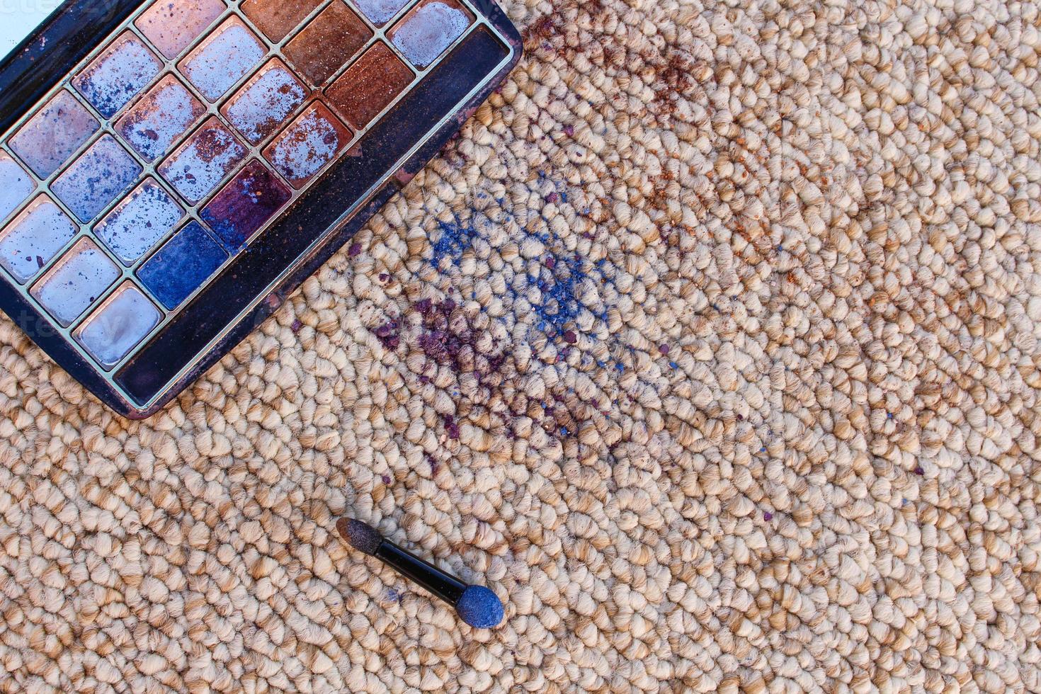 Eye shadow fell and scattered on carpet. Top view. photo