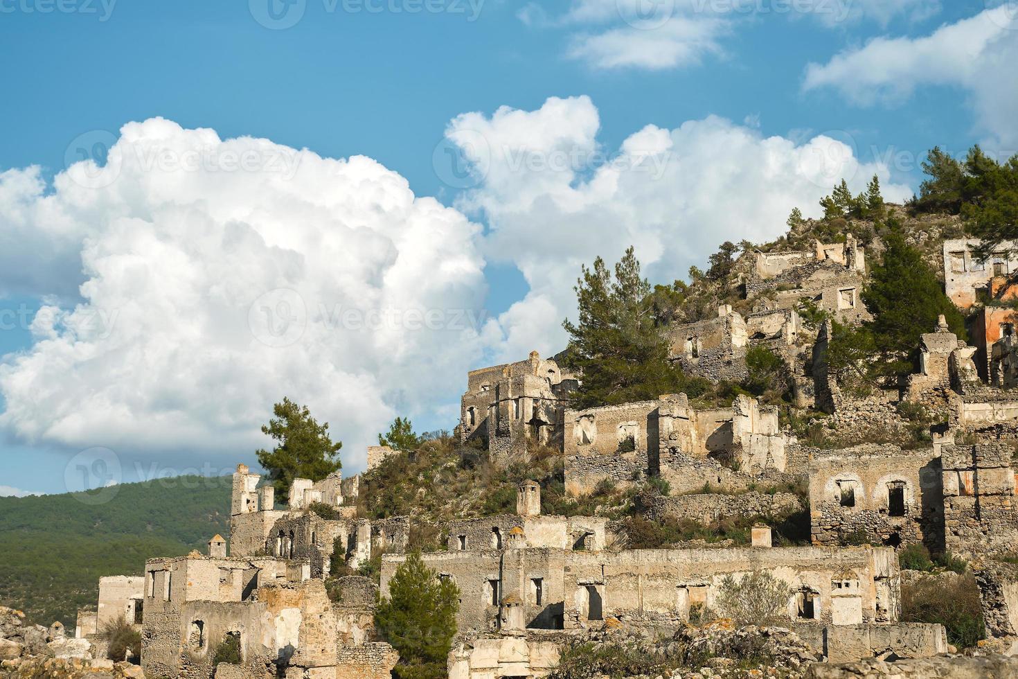 The ruins of the abandoned Greek city of Levissi near the village of Kayakoy in Fethiye Turkey, against the backdrop of cumulus clouds, the tragedy of wars. Site of the ancient city of Karmilissos photo