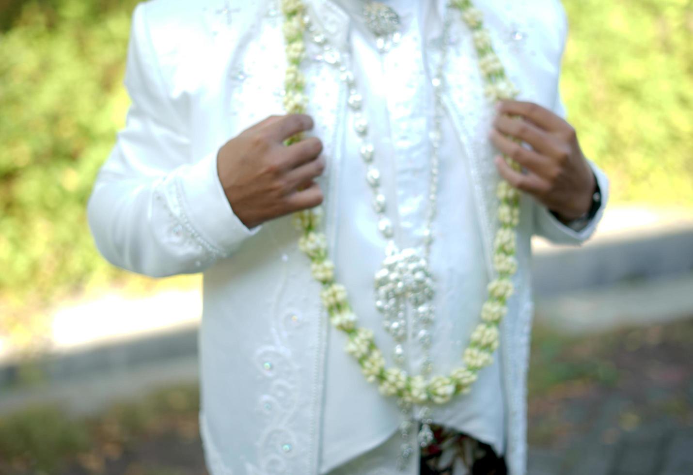 Groom Holding Jasmine and Magnolia Flower Necklace photo