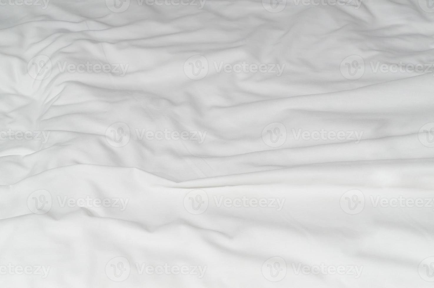 White crumpled or wrinkled bedding sheet or blanket with pattern after guest's use taken in hotel, resort room with copy space, Untidy blanket background texture photo