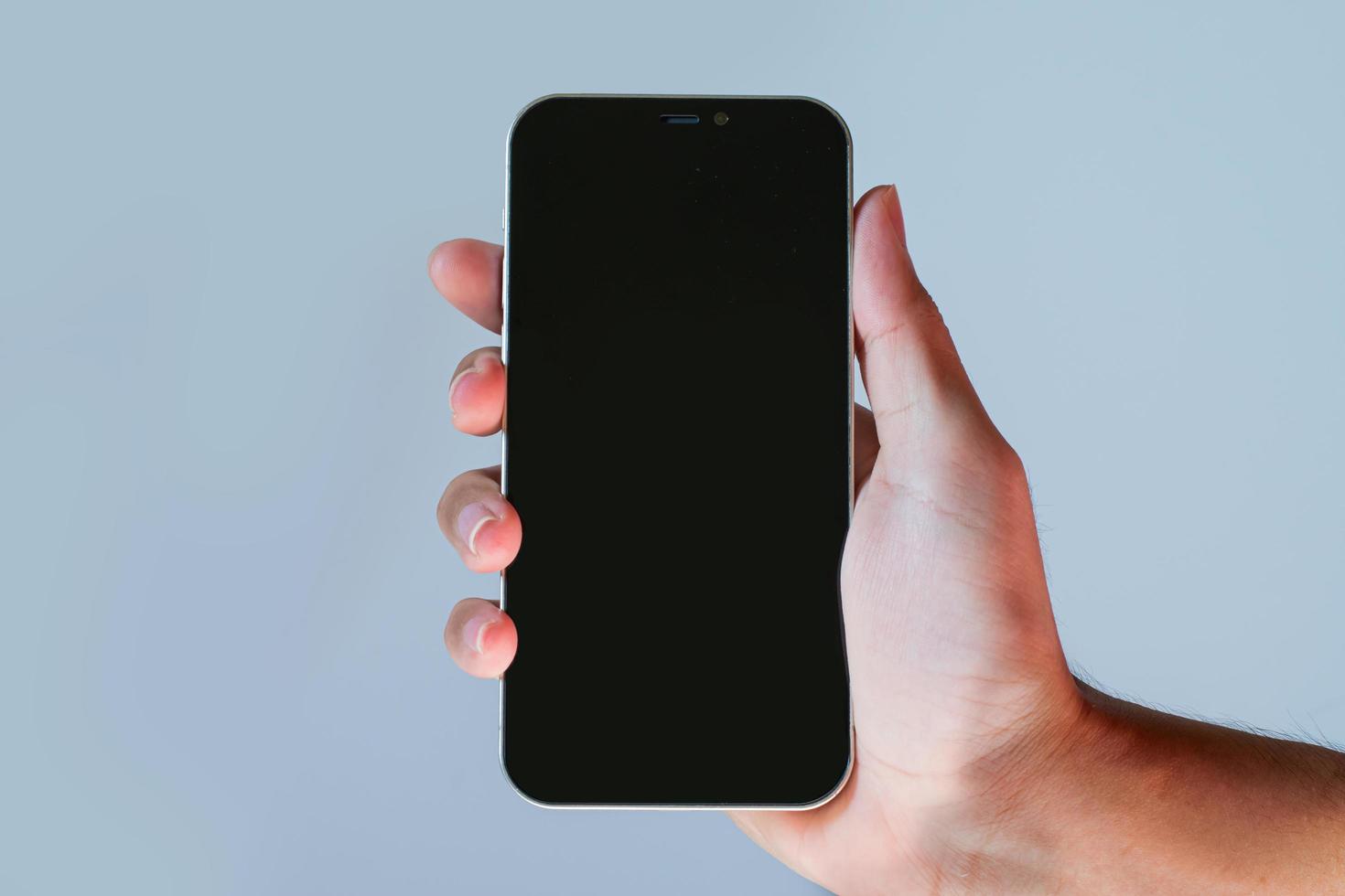 empty screen mobile phone. Close-up hand holding cell phone isolated on blue background. hand holding a blank-screen smartphone. photo