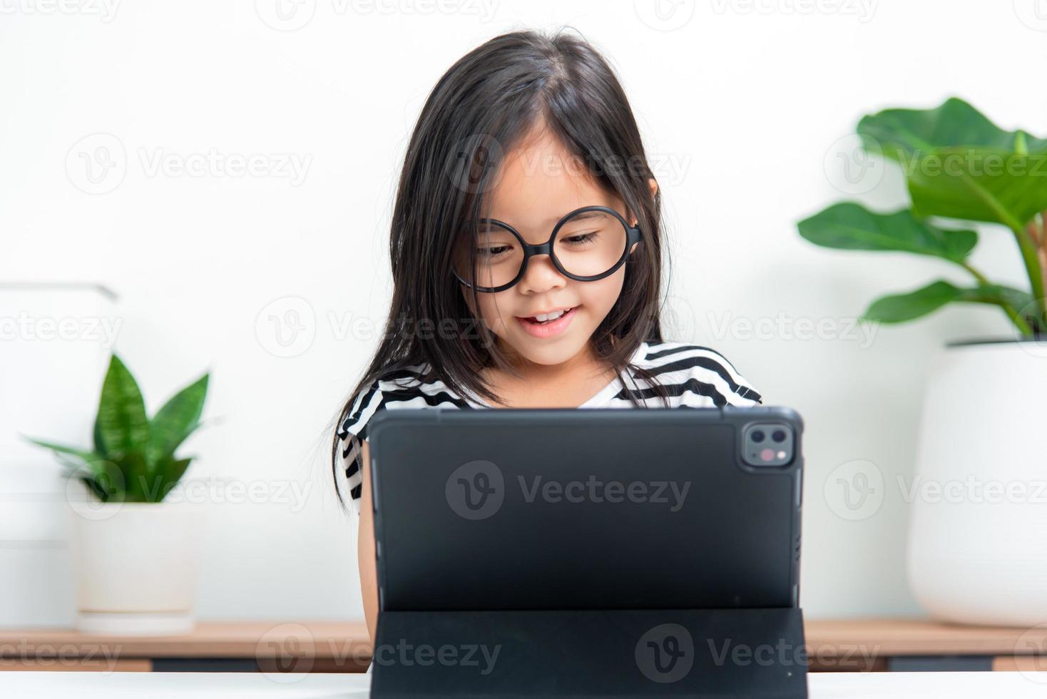 Asian child girl student wow excited on video call learning to studying online class or person learn from home school with tablet photo