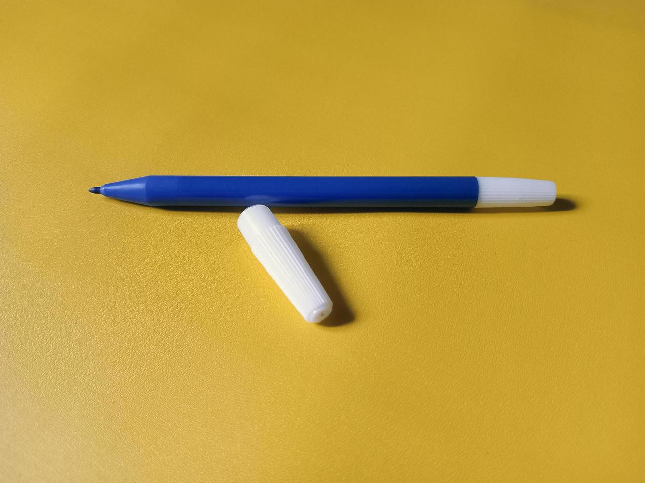 blue pen marker isolated on yellow background photo