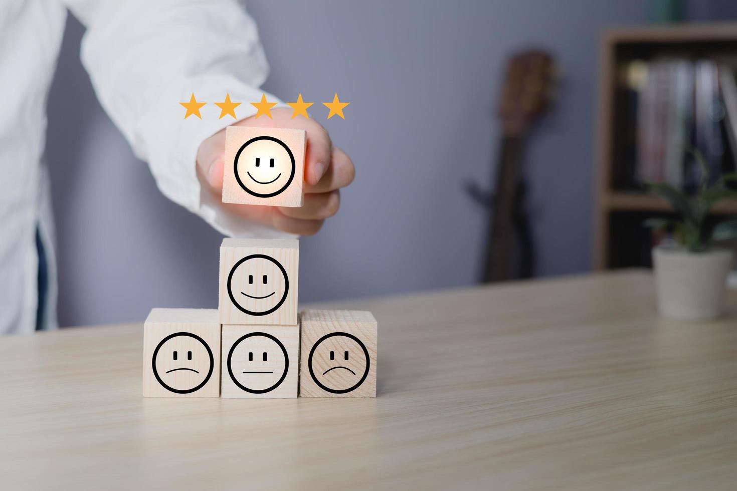 Hand of a businessman chooses a smile face on wood block circle.Customer service experience and business satisfaction survey.rating very impressed.Satisfaction survey concept.five Star Satisfaction photo