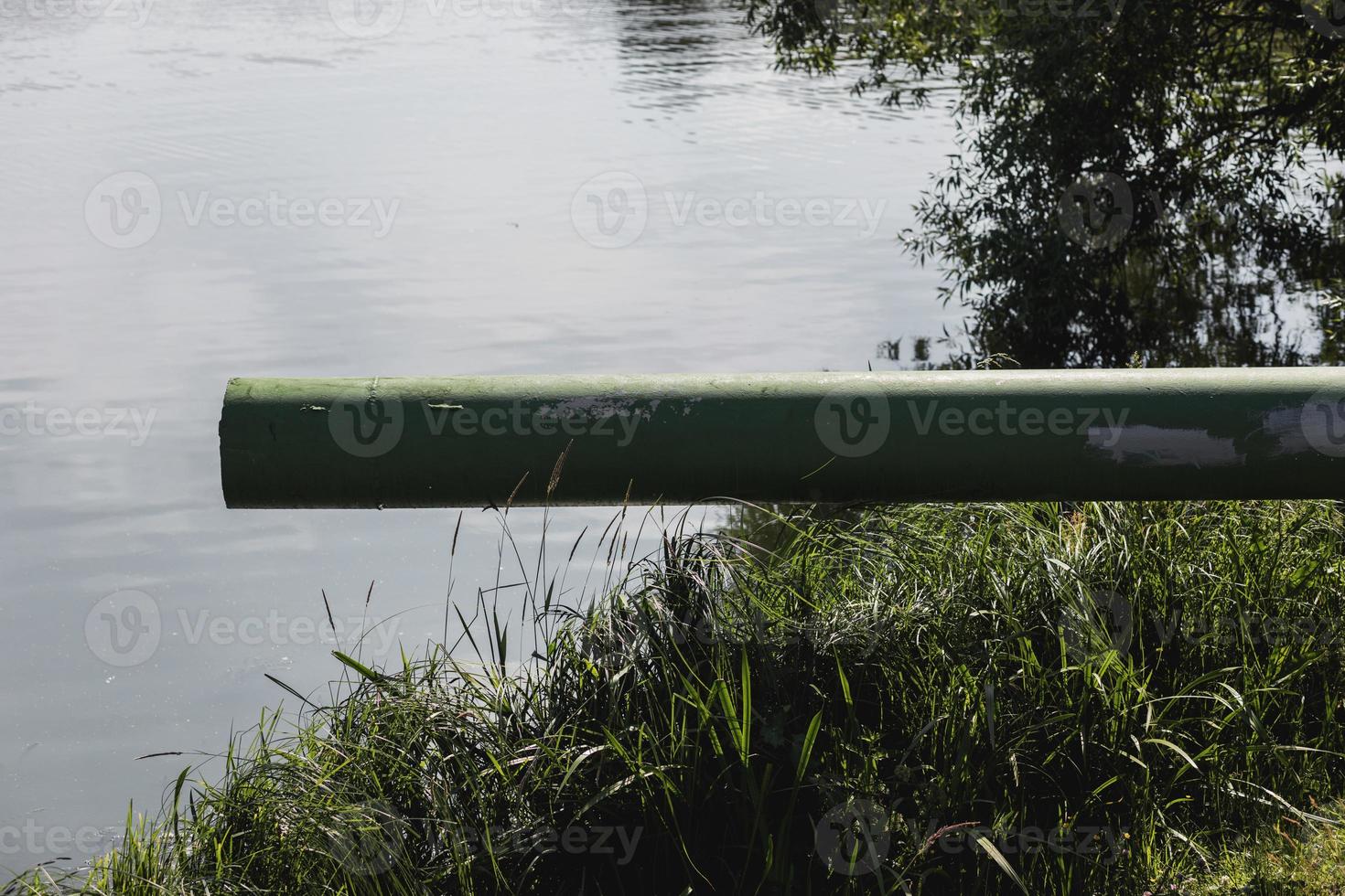 Draining sewage from pipe into river photo