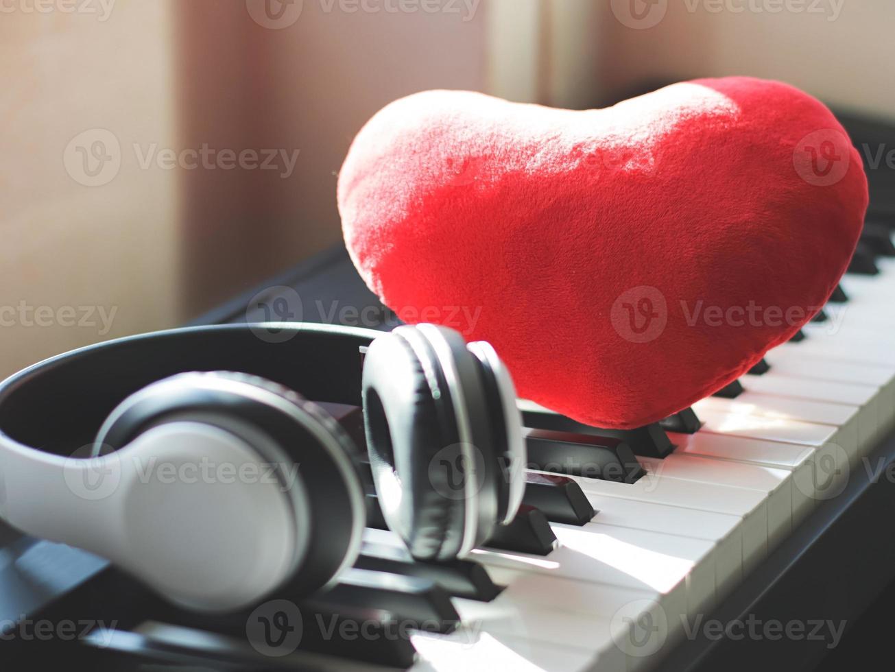 red heart shape pillow with headphones on piano keyboard. Love song or valentine's day concept. photo