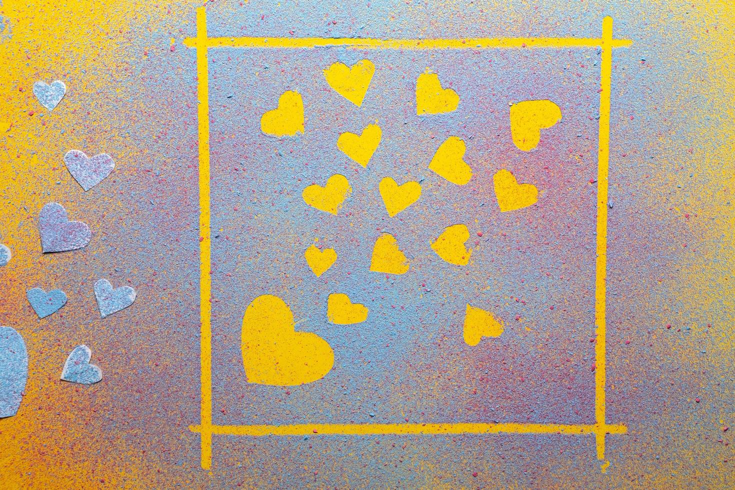 Día de San Valentín. corazones símbolo de amor en un marco y junto a él, hechos de polvo brillante multicolor, sobre un fondo amarillo. foto