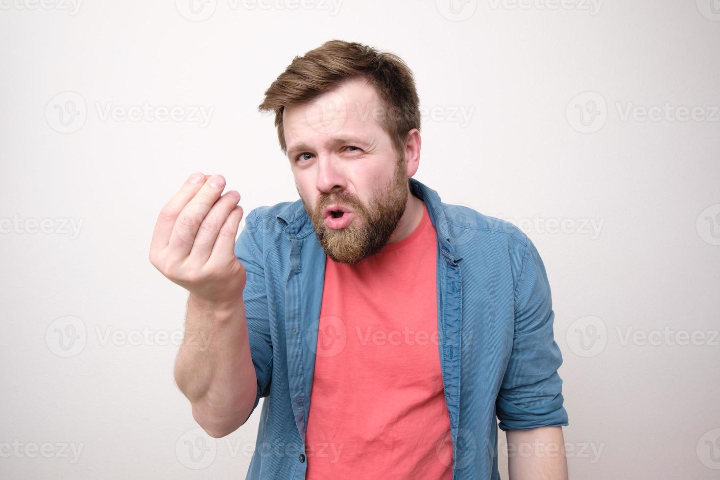 un hombre caucásico descontento jura a alguien y hace un gesto con la mano. Fondo blanco. foto