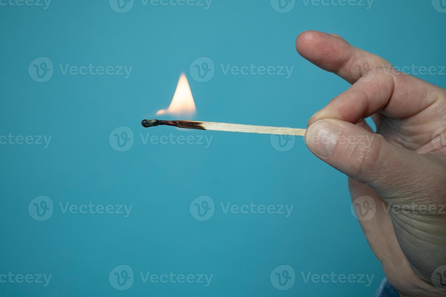Burning match. Flame on the head and matchstick, on a blue background. photo
