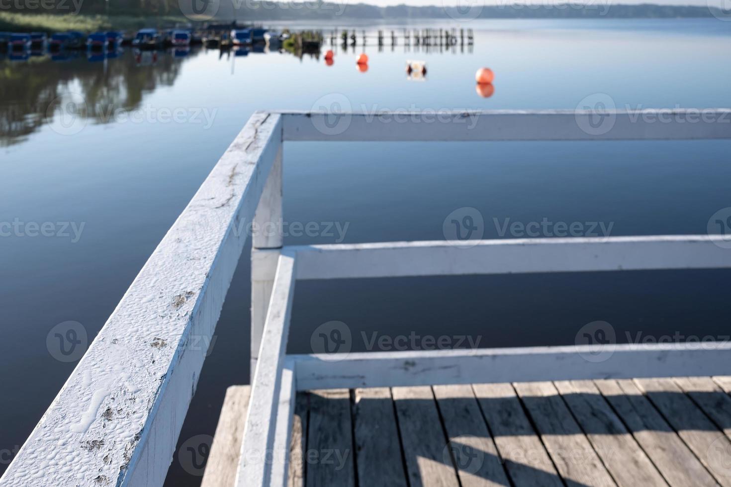 Wooden jetty with a railing to prevent falling into the water, against the backdrop of a lake. photo