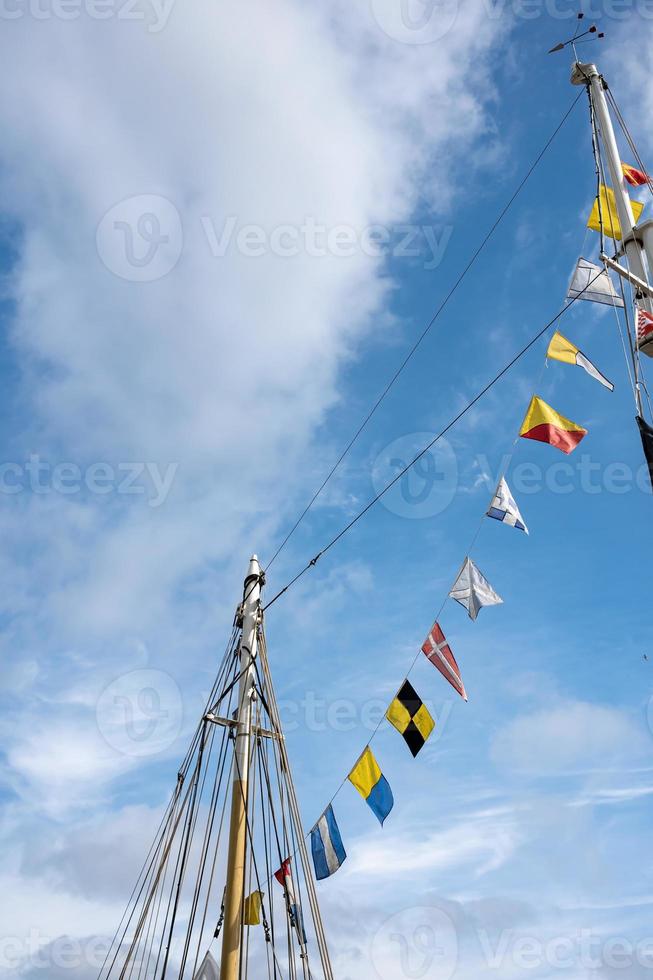 Flags of European countries hang on the mast of the yacht, against the blue sky. Bottom view. photo