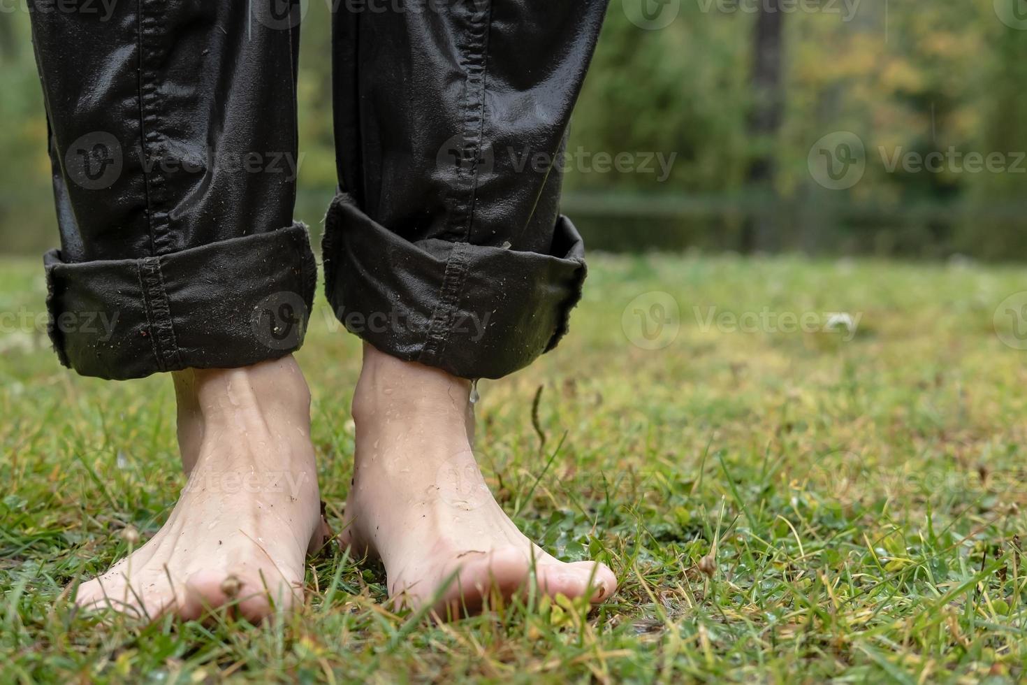 los pies femeninos descalzos se paran en un césped húmedo, después de la lluvia, en el patio. de cerca. foto