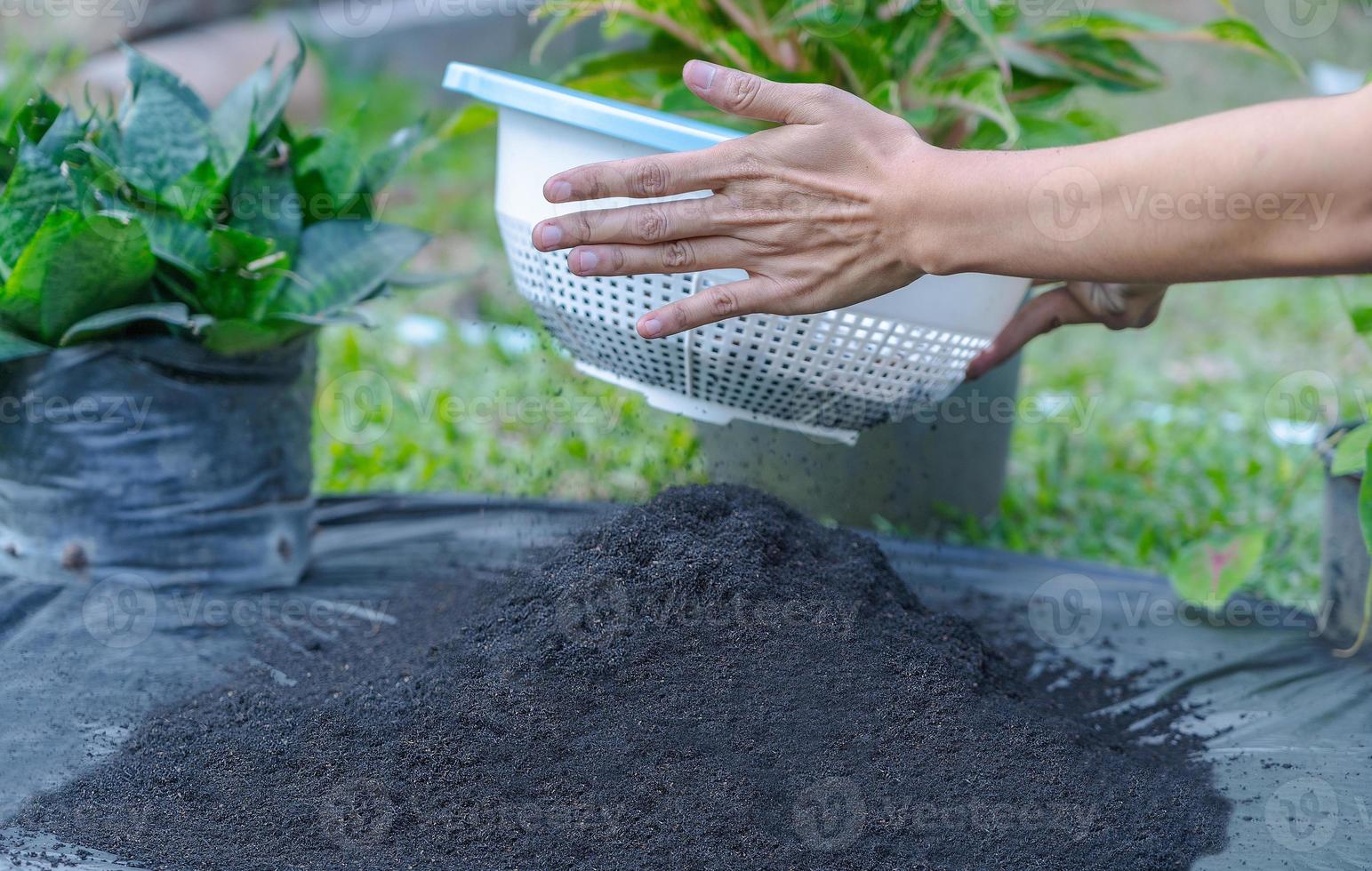 Preparation of soil mixture from fertile compost, humus and vermiculite on  black garbage bag floor in garden. Mixing the soil components for the preparation of the substrate for transplanting plants. photo
