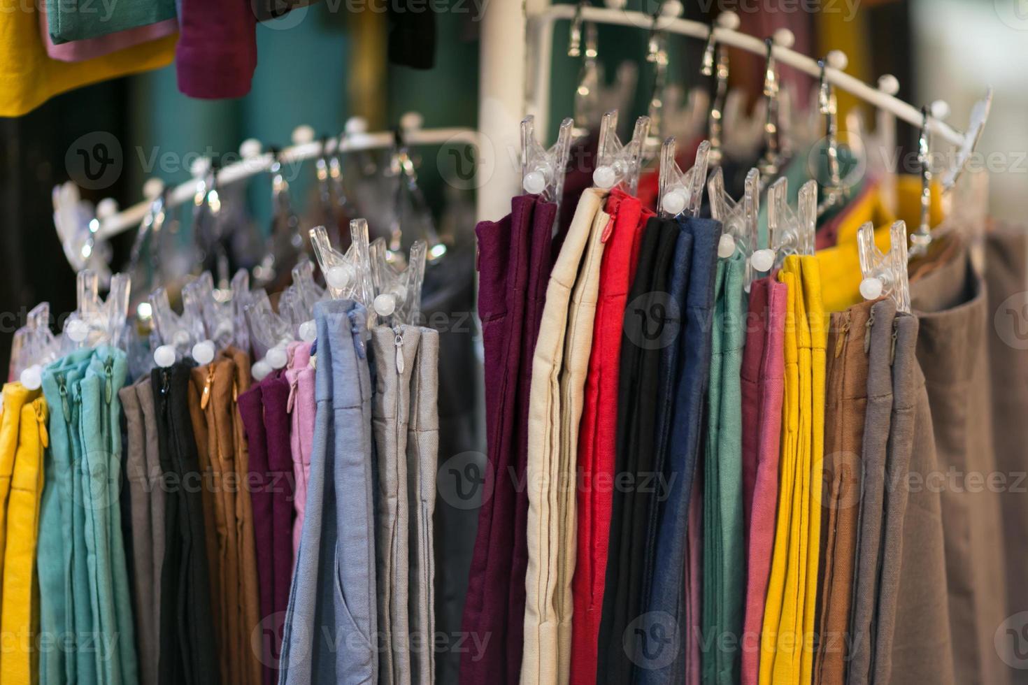 Clothes that are arranged on shelves and hangers photo