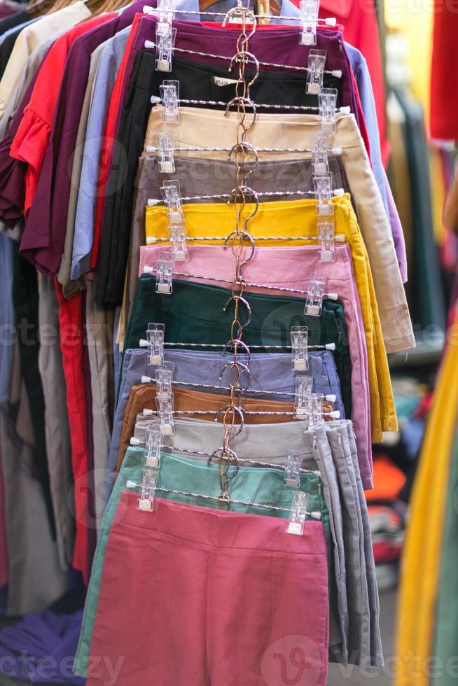 Clothes that are arranged on shelves and hangers photo