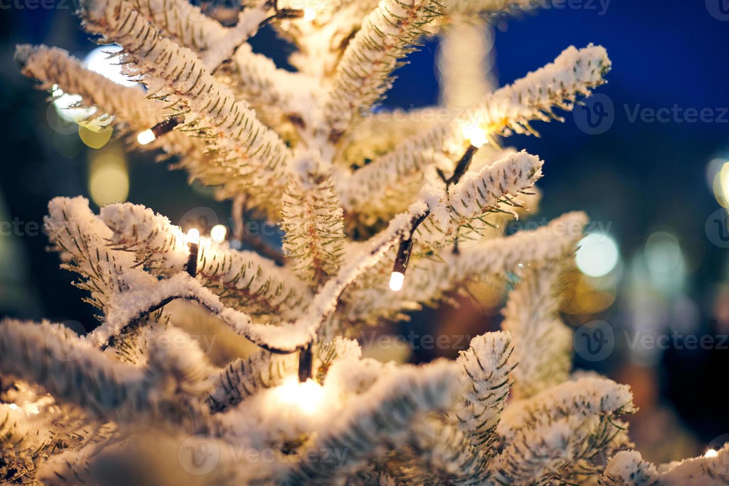 Christmas tree covered snow with yellow garlands lights and bokeh copy space with sparkled bokeh photo