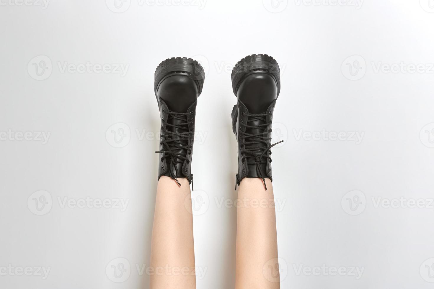 Woman legs in black combat boots on high heel platform with lug soles upside down, white background photo