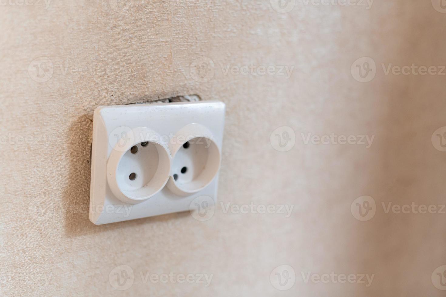 AC power double socket on wall, bad incorrectly installed, copy space. Socket for europlug type. Violations of safety standards. Fire-hazard. photo