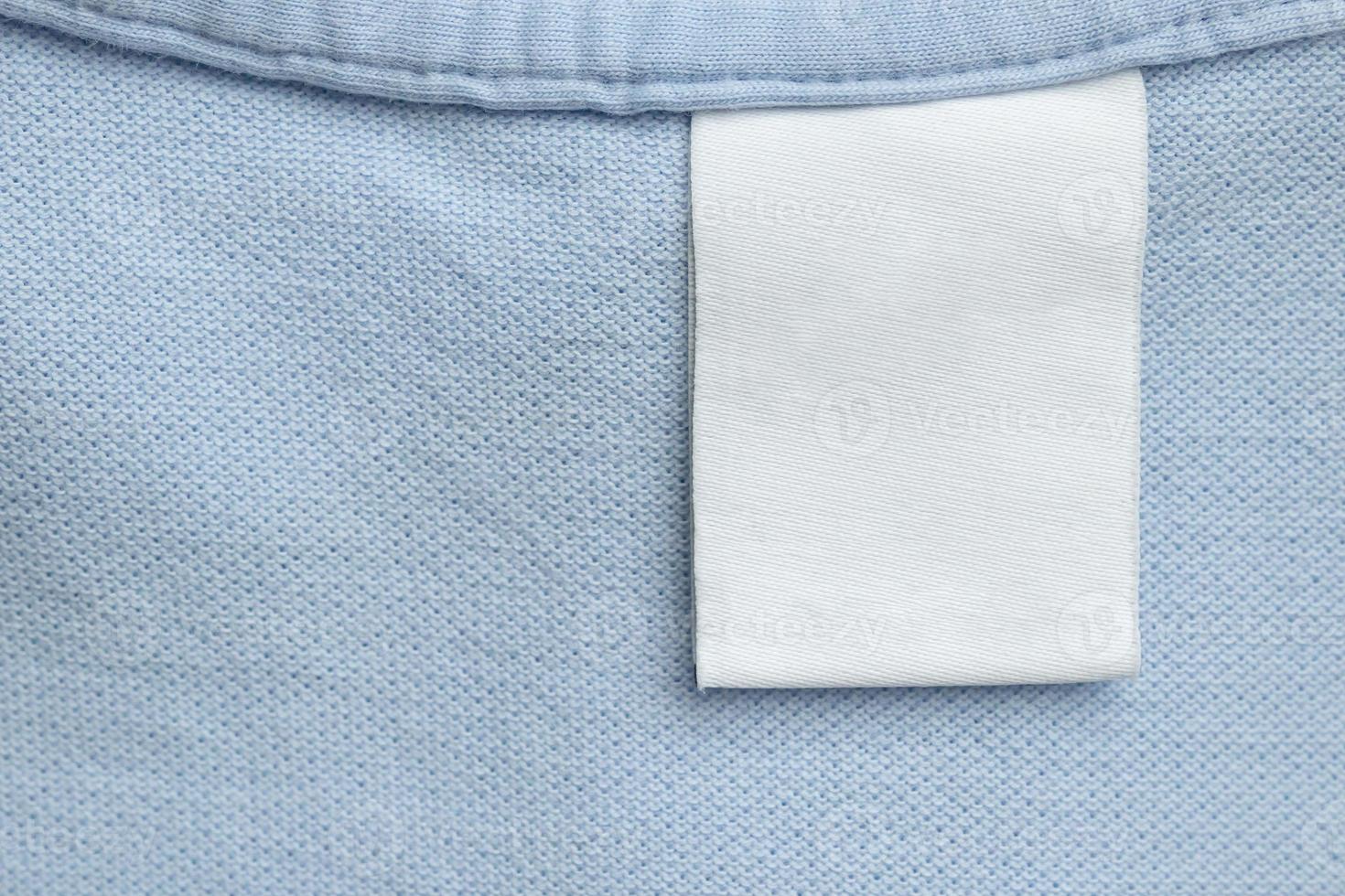 White blank laundry care clothes label on blue shirt fabric background photo