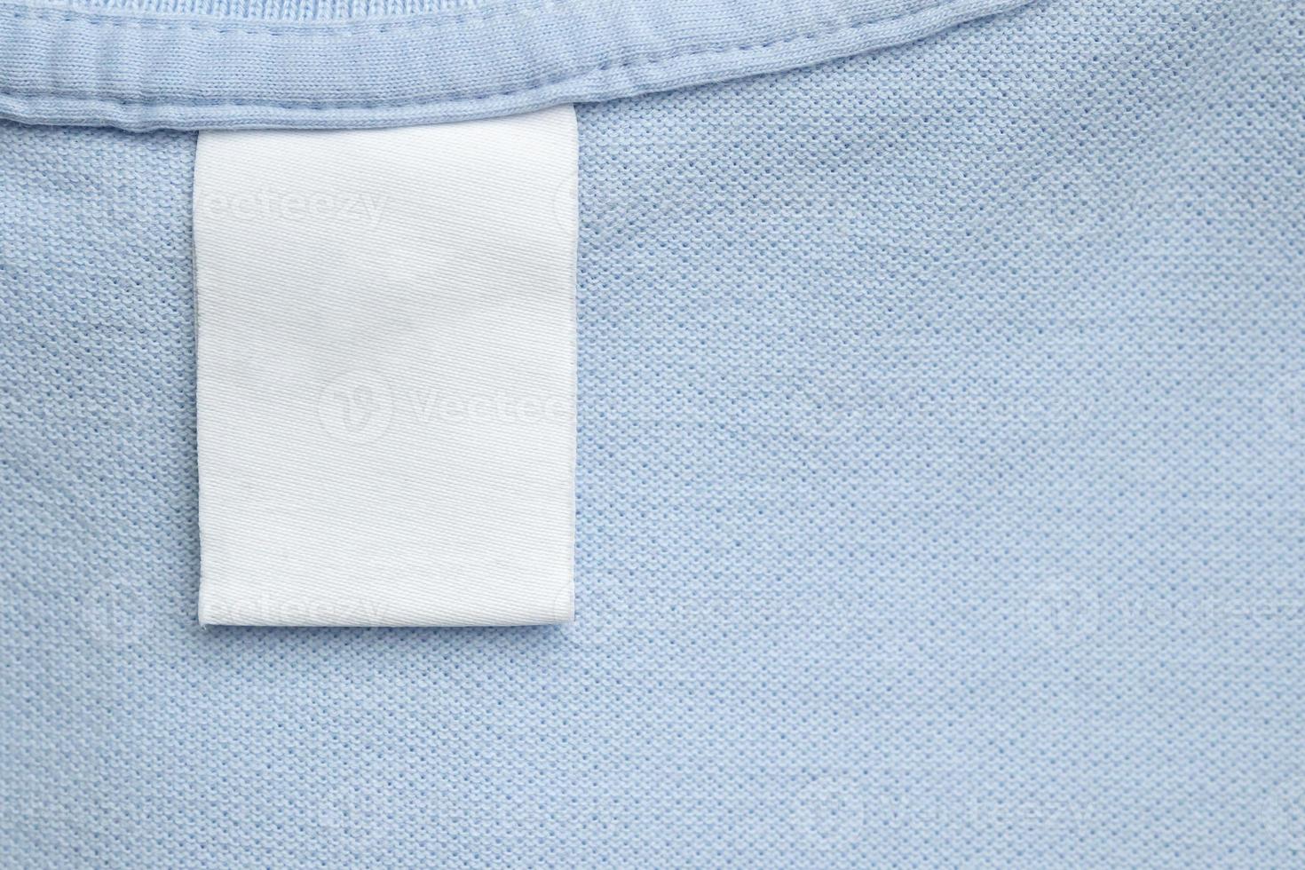 White blank laundry care clothes label on blue shirt fabric background photo