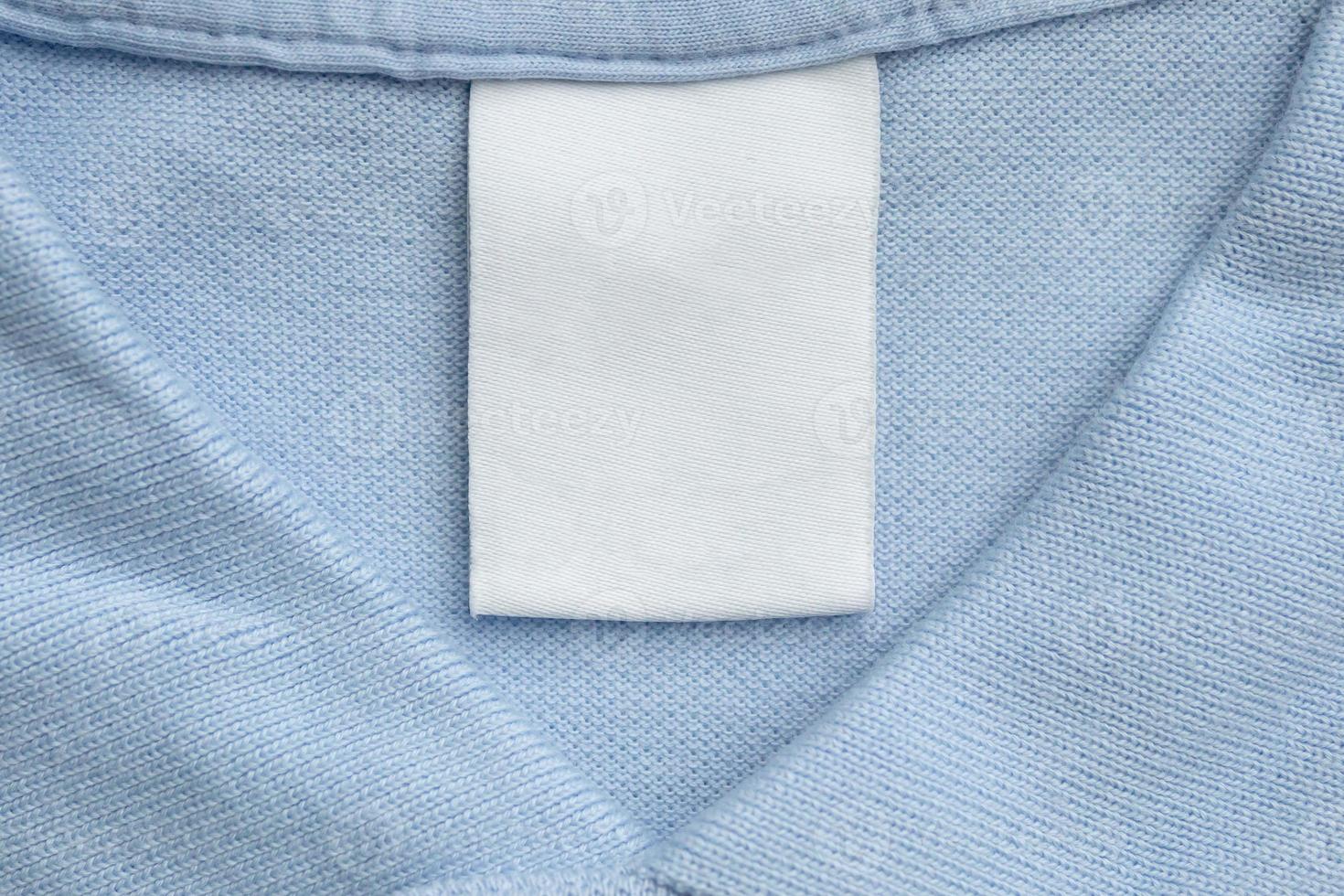 etiqueta de ropa blanca en blanco para el cuidado de la ropa sobre fondo de tela de camisa azul foto