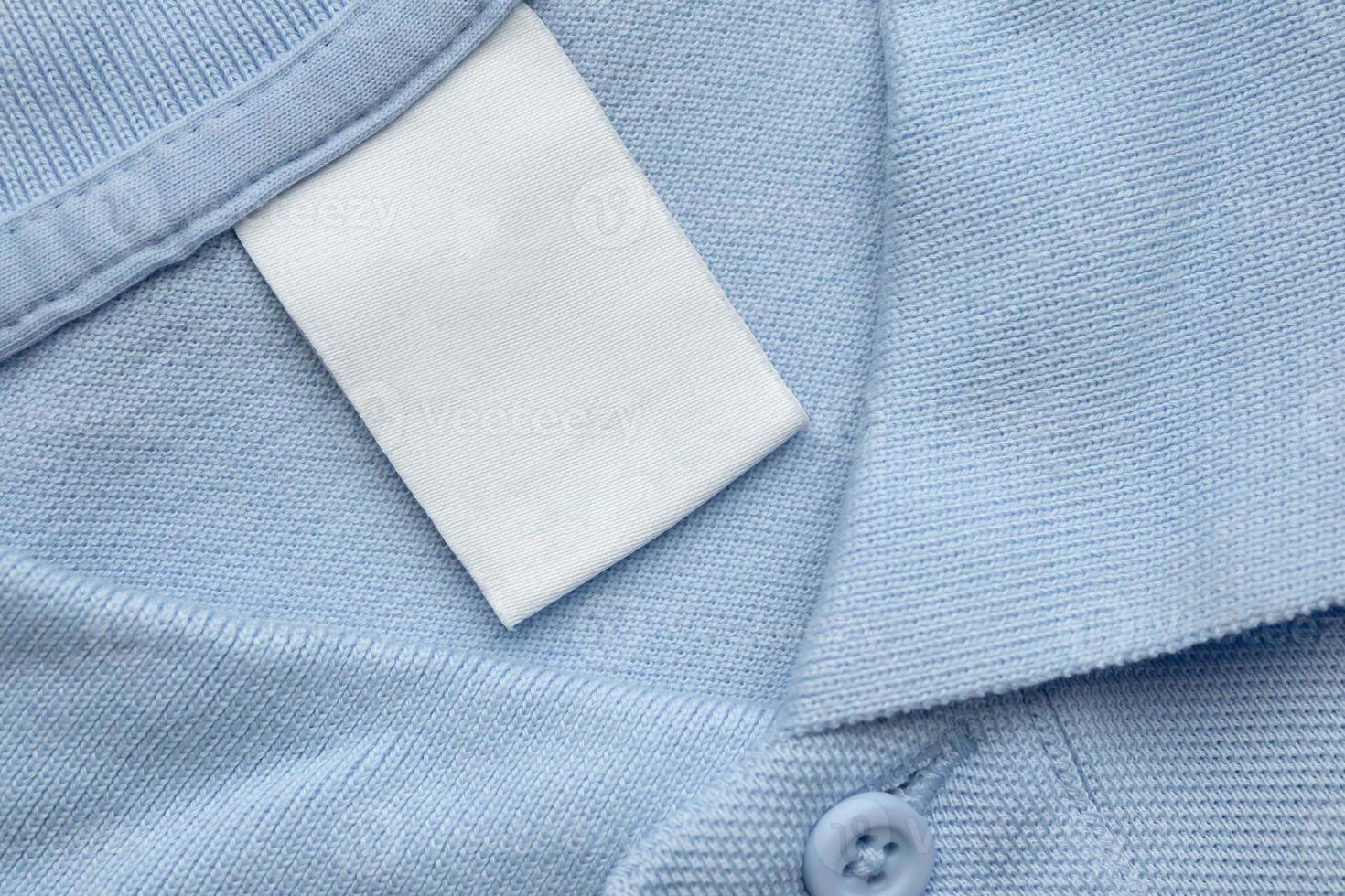 etiqueta de ropa blanca en blanco para el cuidado de la ropa sobre fondo de tela de camisa azul foto