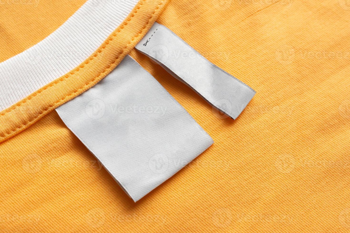 Blank white laundry care clothes label on yellow fabric texture background photo