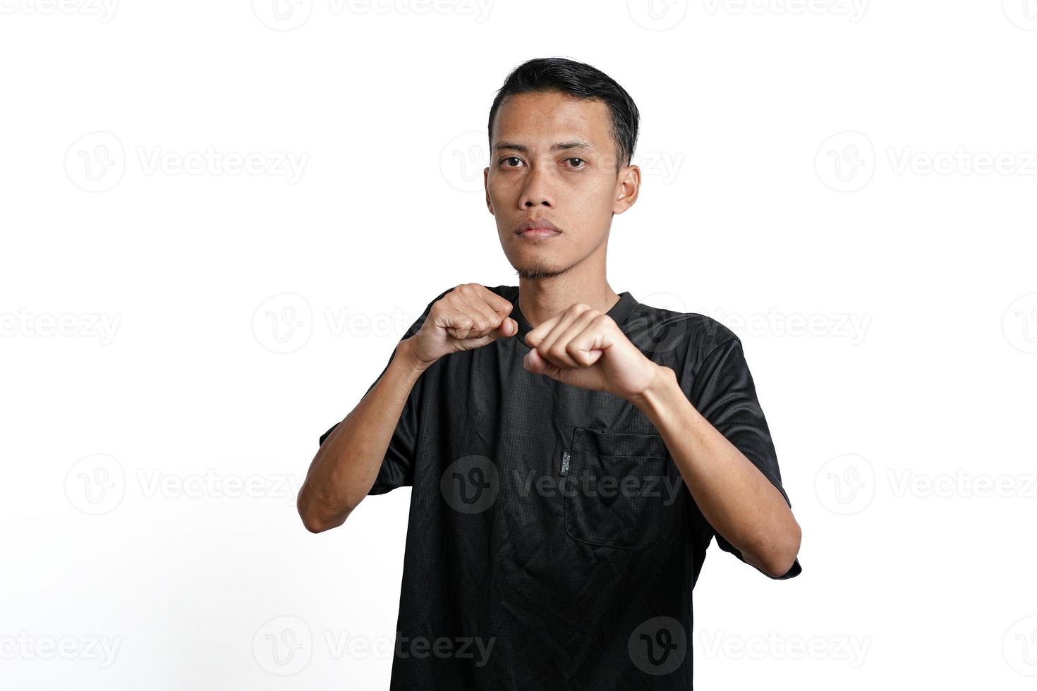 Asian man wearing black training t-shirt, gesturing to fight. Isolated by white background photo