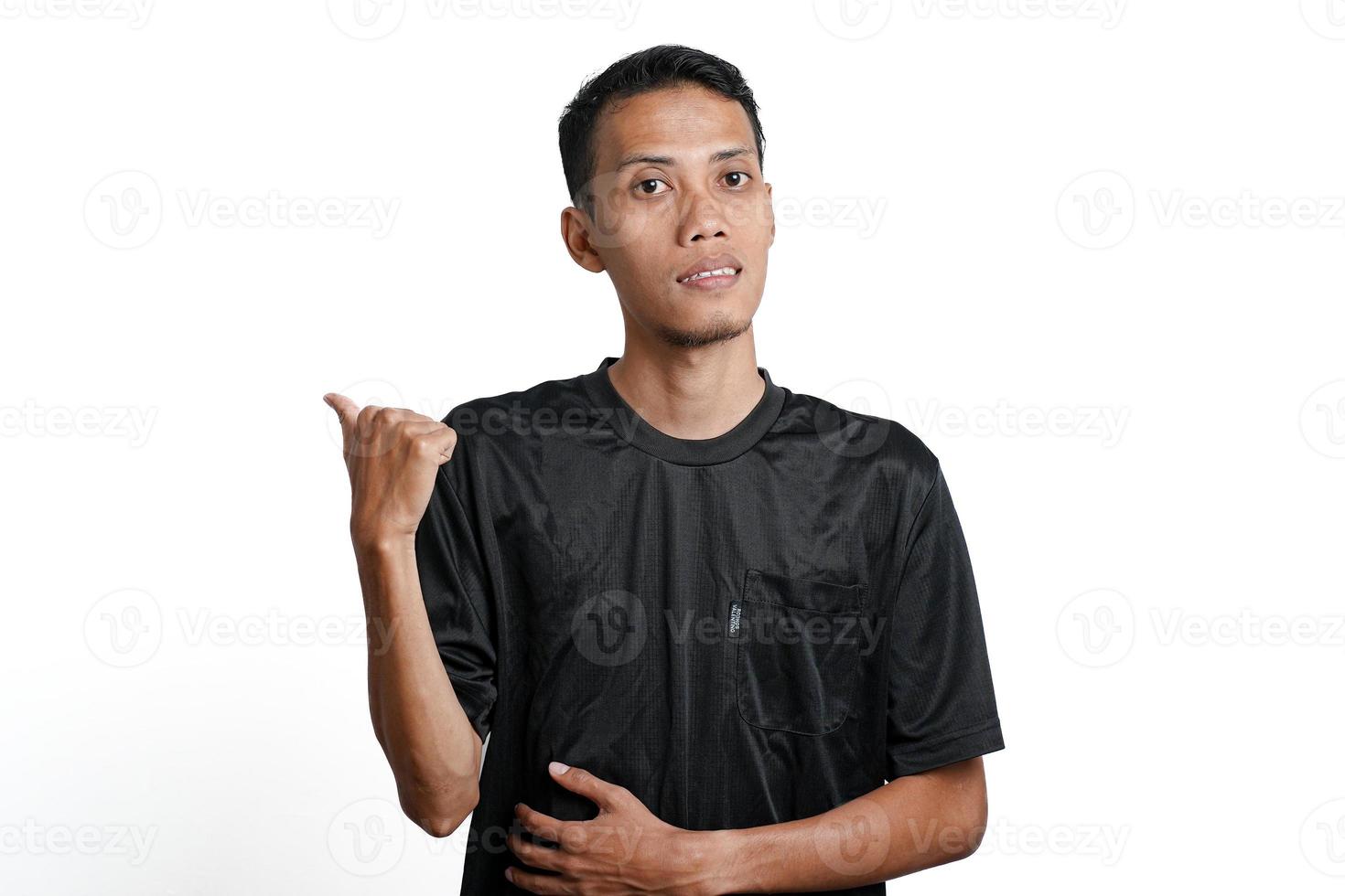 excited asian man wearing black training t-shirt, pointing to copy space. Isolated by white background photo