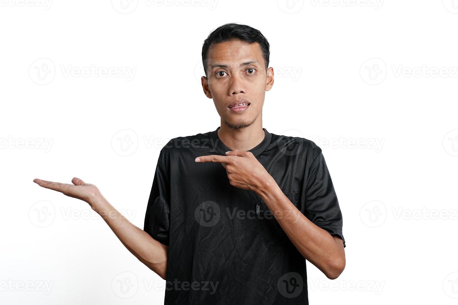 excited asian man wearing black training t-shirt, pointing to copy space. Isolated by white background photo