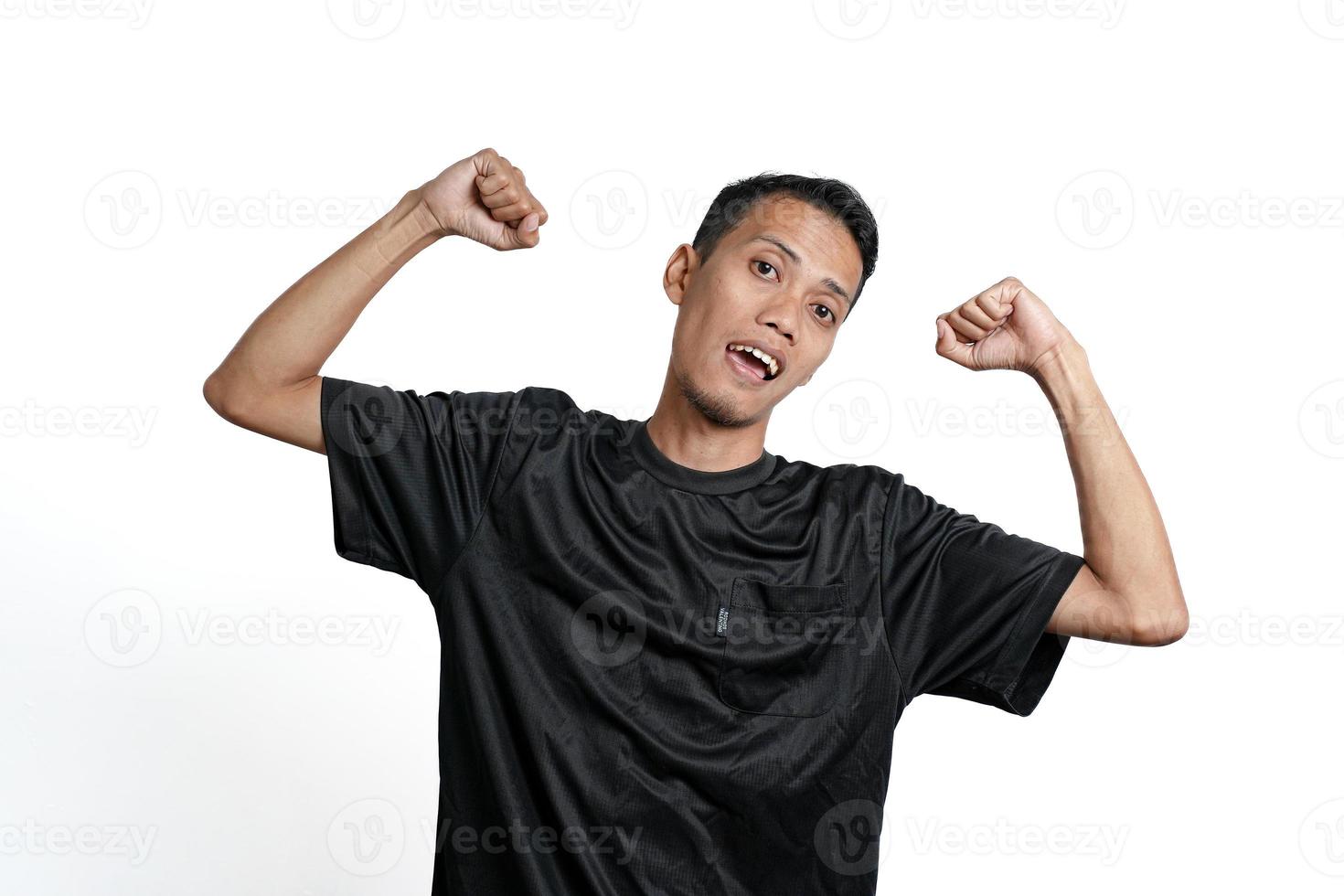 hombre asiático con camiseta negra de entrenamiento, mostrando una postura fuerte con brazos y músculos levantados. aislado por fondo blanco foto