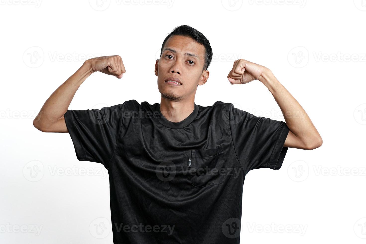 asian man wearing black training t-shirt, showing a strong stance with raised arms and muscles. Isolated by white background photo