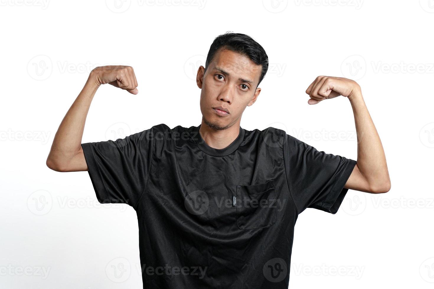 asian man wearing black training t-shirt, showing a strong stance with raised arms and muscles. Isolated by white background photo