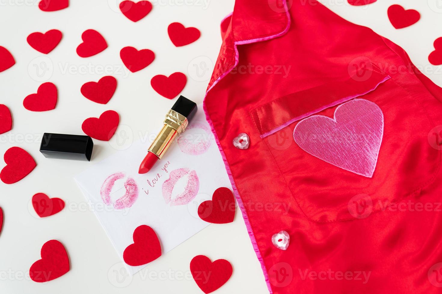 The inscription I love you on a white envelope with a print of lips in red lipstick on a background of small red hearts and a red shirt. Valentine's day concept. photo